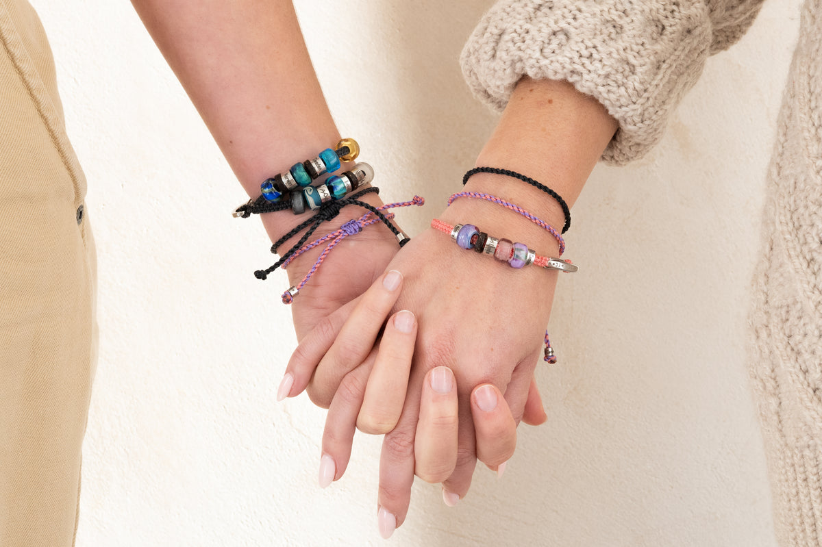 El Camino Coral and Lavender Journey Bracelets being worn with other El Camino travel bracelets. The perfect gift for your travel companion.
