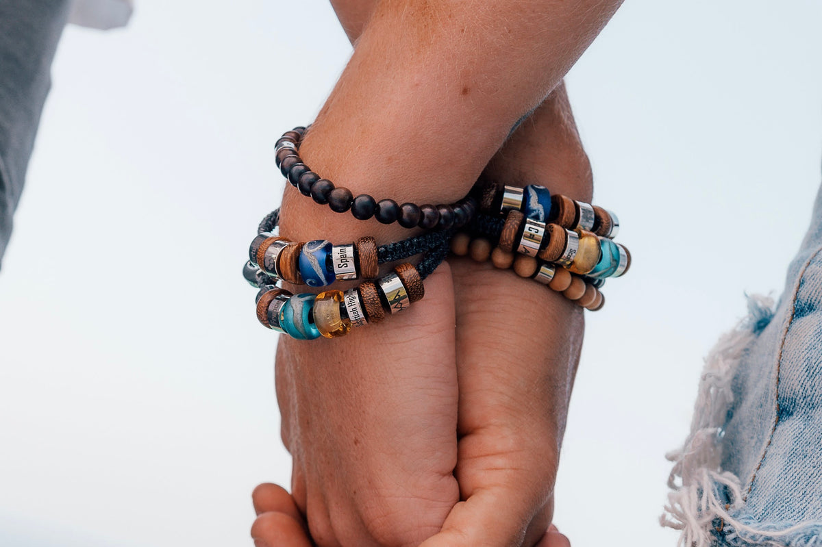El Camino Double Travel Bracelets with Atlantic Ocean, Spain, Pacific Ocean, Middle East and Scottish Highlands charms Steps travel memory beads. Also showing light wood spacers, dark wood bracelet and natural wood bracelet